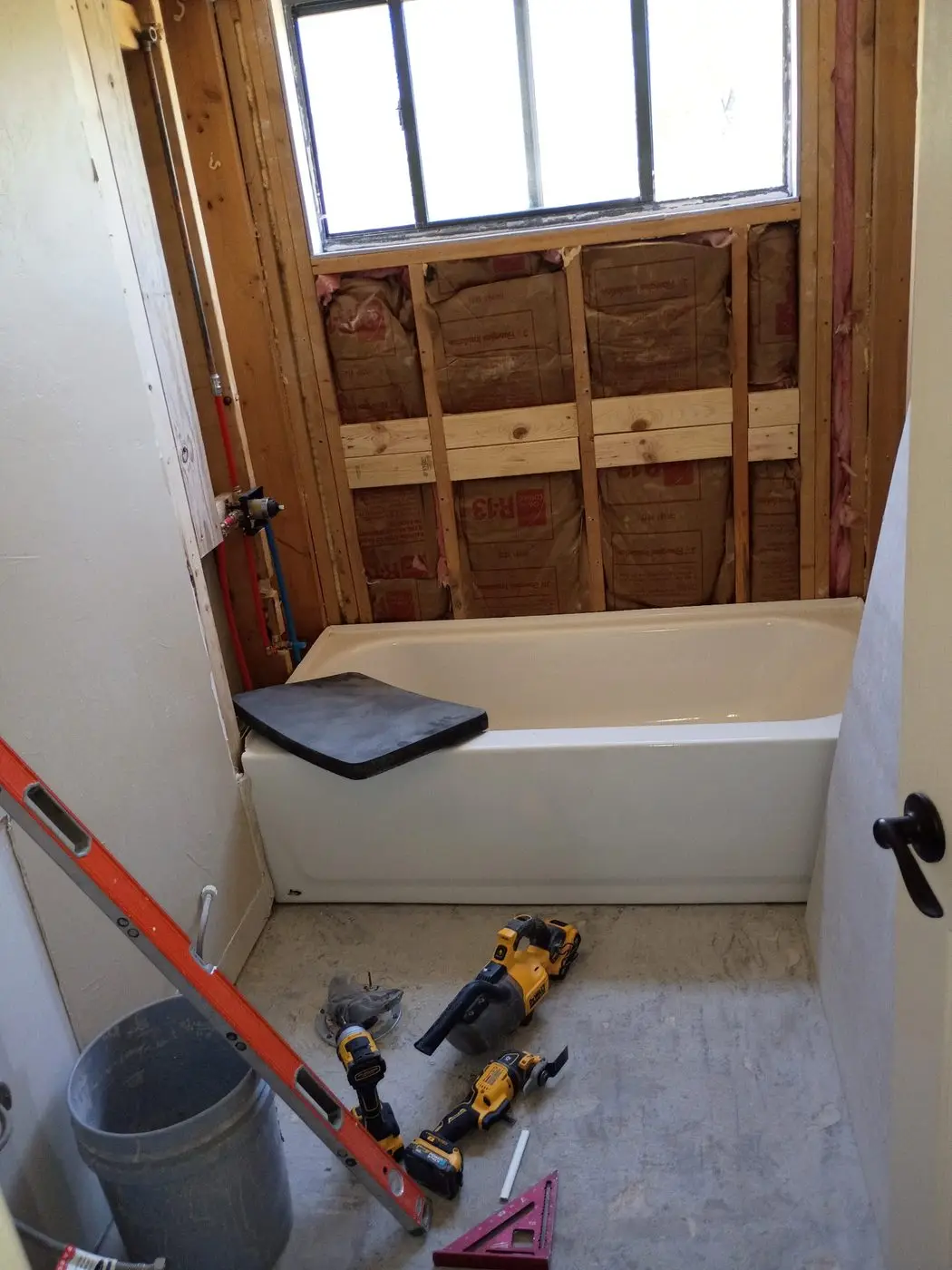 Bathroom remodel in progress with new tub and framed window opening